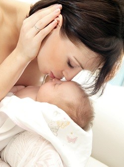 Mammma mentre bacia il suo bambino avvolto da una coperta