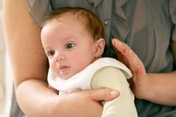 madre che cerca di far passare il singhiozzo con dei colpetti sulla schiena del suo bimbo