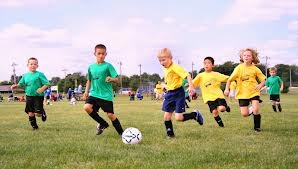 gruppo di bambini mentre gioca a calcio su di un prato